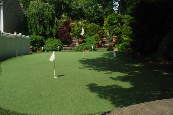 Fresno Synthetic grass golf green with flags in a landscaped backyard